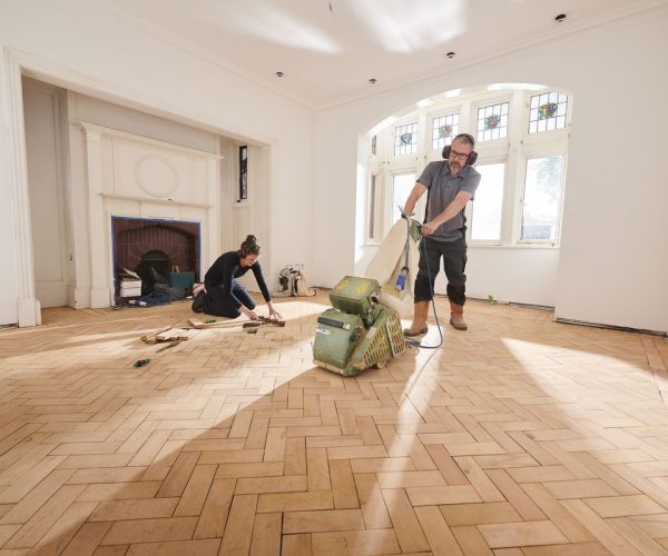 two workers repair and restore a parquet period floor
